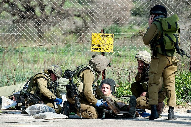 Israeli soldiers treat a wounded comrade Wednesday near the border with Lebanon after a missile fired by Lebanese Hezbollah militants struck a convoy.