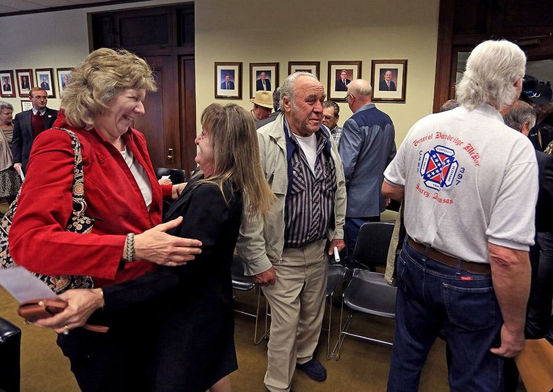 Roberta Spencer (left) of Judsonia and Vickie Bird of Searcy celebrate Wednesday near Spencer’s husband, Dewey, (right) who wears a shirt with a Confederate flag on it, after a legislative committee discussion on Gen. Robert E. Lee’s birthday. 