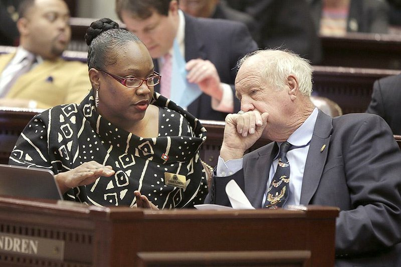 State Reps. Vivian Flowers, D-Pine Bluff, and Kim Hendren, R-Gravette, visit Thursday in the House chamber. The House passed legislation Thursday cutting the income-tax rates for middle-class Arkansans. 