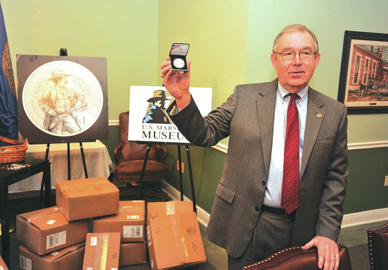 Jim Dunn, president and CEO of the Marshals Museum in Fort Smith, displays one of the comparative coins that arrived Thursday during a news conference at the office in Fort Smith. Thousands of coins arrived in Fort Smith on Thursday to be made available to buy in Fort Smith or online. Money from the coin sales will be used to help build the $50 million museum.