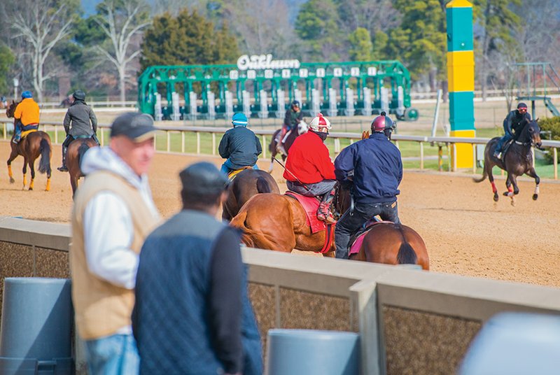 Horse trainers and owners stand along the track at Oaklawn Park to watch a recent practice session for horses being stabled the the Hot Springs racing and gambling establishment.