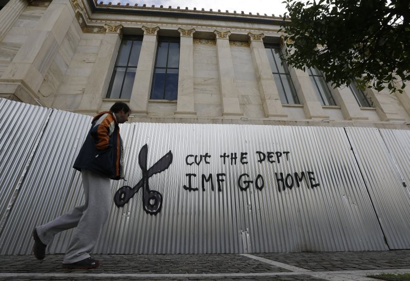 A pedestrian passes anti-austerity graffiti in front of Athens Academy on Thursday, Jan. 29, 2015. The European Parliament's president is to be the first European official to visit Athens, a day after announcements by Greece's nascent radical left government on rolling back a series of key budget commitments sent the country's stock market plummeting. 