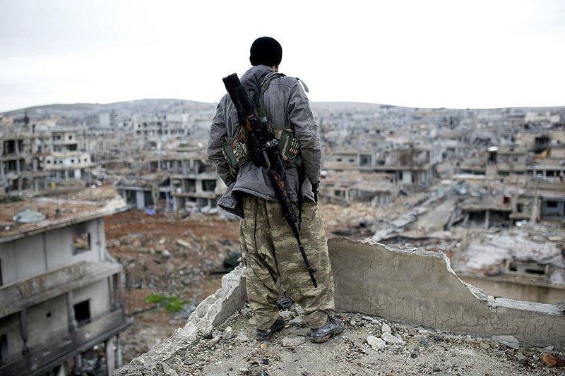 A Syrian Kurdish sniper looks down on the destruction in Kobani, Syria, which the Islamic State on Saturday acknowledged being driven out of while vowing to retake the city. 