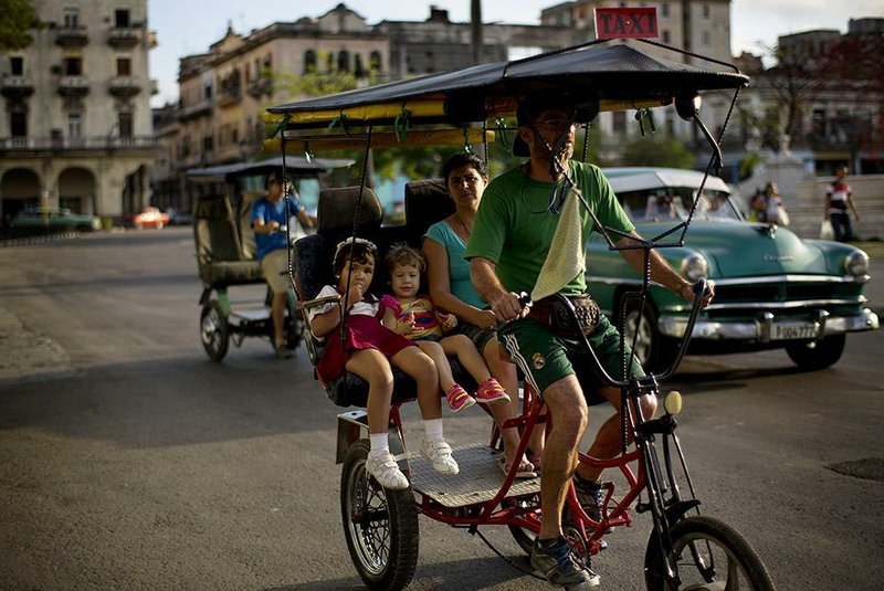 A woman and her children take a leisurely rickshaw ride through the center of Havana in mid-January. 