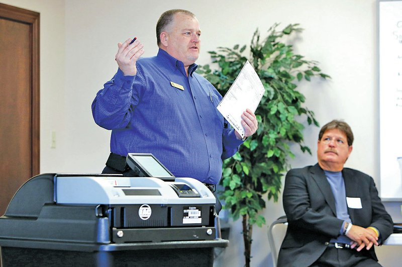 NWA Democrat-Gazette/DAVID GOTTSCHALK Paul Griego (right), with Unisyn Voting Solutions, watches a presentation by Brent Wagoner with Henry M. Adkins &amp; Son about one of three paper-based voting machines Tuesday at the Washington County Courthouse in Fayetteville. Officials and election commissioners from several counties gathered information about products available to replace the voting machines and ballot counters in use across Arkansas.