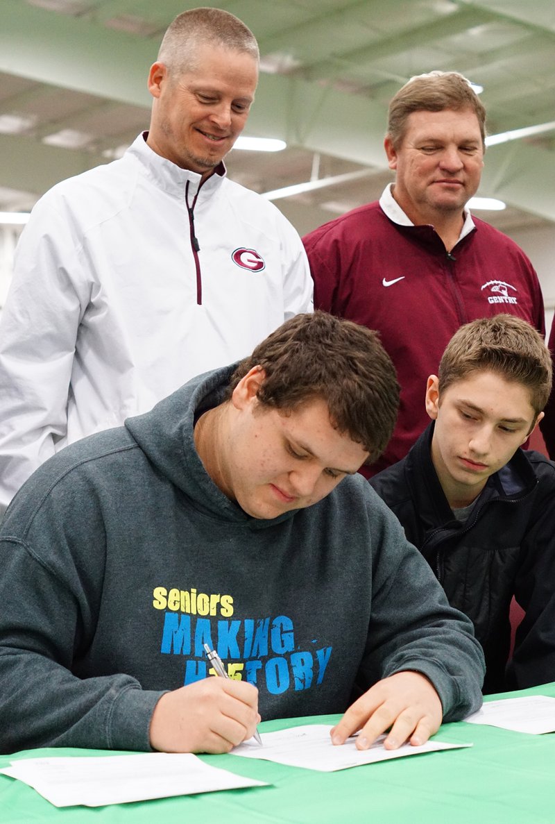 Zach Ellis, Gentry senior, signed to play football next year for the University of Arkansas in Monticello while his brother, Devon Ellis, and Gentry coaches Brian Little and Daniel Ramsey looked on during a signing ceremony on Wednesday, Feb. 4, 2015, at Gentry High School.