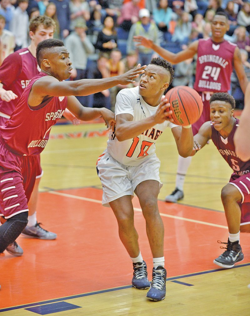 NWA Democrat-Gazette/BEN GOFF Zach Burton (left) of Springdale guards Lexus Hobbs of Rogers Heritage on Friday during the game in War Eagle Arena at Rogers Heritage.