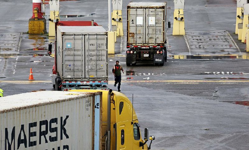 One driver hurries around his truck as another heads toward an empty slot while arriving to drop cargo at the Port of Seattle Friday, Feb. 6, 2015, in Seattle. Companies that handle billions of dollars of cargo at West Coast seaports said they will hire far fewer workers this weekend, the latest escalation in a contract dispute with dockworkers that threatens to shut down a vital link in U.S.-Asia trade. The announcement could foreshadow a full port shutdown as soon as Monday, or be a hardball bargaining tactic designed to force a contract after nine months of talks. (AP Photo/Elaine Thompson)