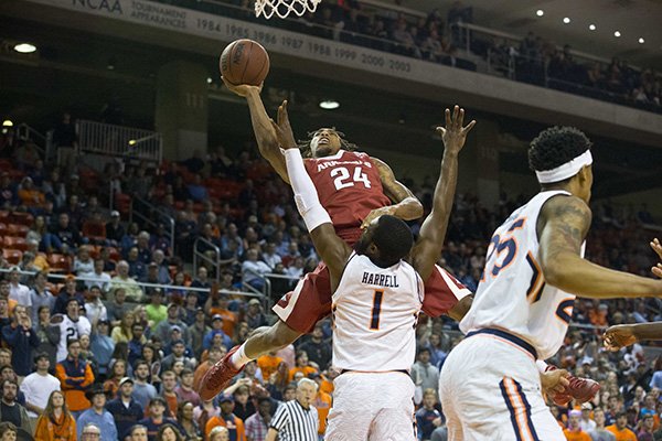Arkansas guard Michael Qualls (24) jumps and scores against Auburn guard KT Harrell (1) during the first half of an NCAA college basketball game, Tuesday, Feb. 10, 2015, in Auburn, Ala. (AP Photo/Brynn Anderson)
