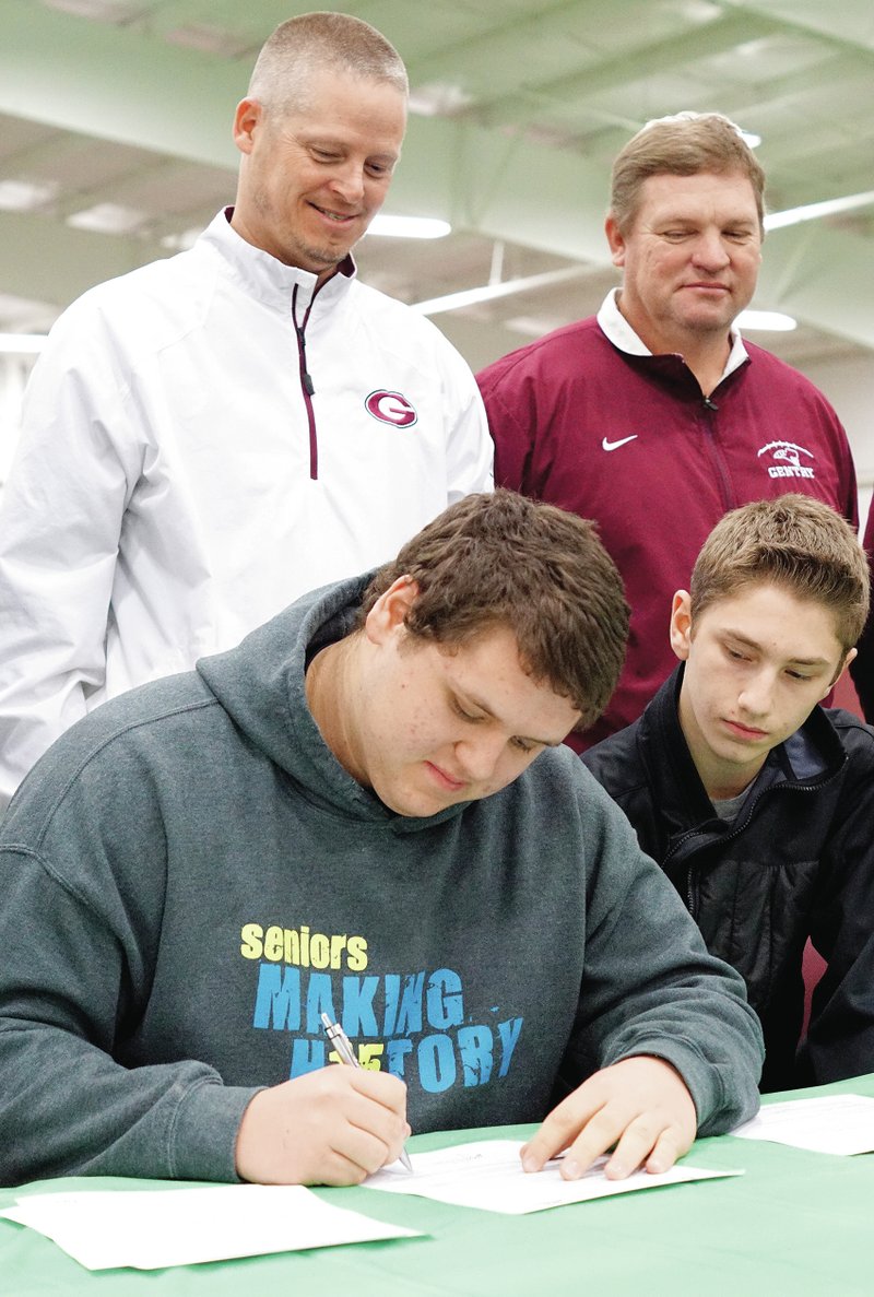 Photo by Randy Moll Zach Ellis, Gentry senior, signed to play football next year for the University of Arkansas in Monticello while his brother, Devon Ellis, and Gentry coaches Brian Little and Daniel Ramsey looked on during a signing ceremony Feb. 4 at Gentry High School.