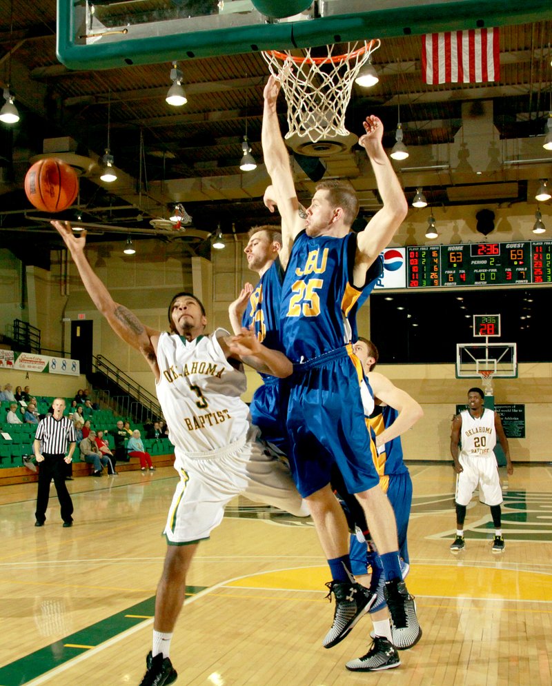 Courtesy of Oklahoma Baptist Sports Information John Brown junior Griffin Brady attempted to block the shot of Oklahoma Baptist&#8217;s D.J. Hervy during Saturday&#8217;s game at the Noble Complex in Shawnee, Okla. John Brown defeated Oklahoma Baptist 76-75.