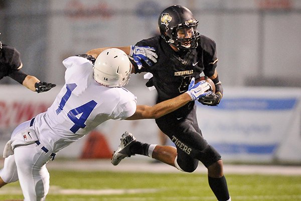 Bentonville receiver Tyrone Mahone breaks the tackle of Kansas City (Mo.) Rockhurst free safety Tyler Benninghoff during a game Friday, Sept. 5, 2014, at Tiger Stadium in Bentonville. 