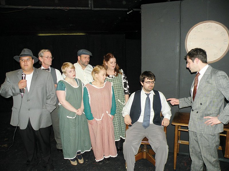 Attorney Leonard Grossman, far right, played by Jake Rivers, questions Dr. Dalitsch, seated, played by Tanner Smith, in this court scene from These Shining Lives. Also shown are, from left, a news reporter, played by Miguel Castillo; factory boss Rufus Reed, played by Tom McLeod; factory worker, Frances, played by Elizabeth Williams; Tom Donohue, played by Chris Harris; factory worker, Pearl, played by Hali Free; and factory worker, Charlotte, played by Wendy Shirar. Not shown is Ashley 
Carnahan, who plays factory worker, Catherine Donohue.
