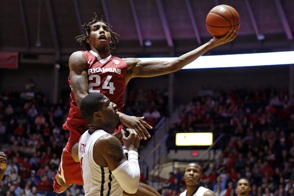 Arkansas guard Michael Qualls (24) lays up a basket past the defense of Mississippi guard Martavious Newby (1) during the second half of an NCAA college basketball game in Oxford, Miss., Saturday, Feb. 14, 2015. No. 24 Arkansas won 71-70. (AP Photo/Rogelio V. Solis)