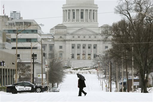 A woman walks across a street in Little Rock, Ark., Monday, Feb. 16, 2015. The National Weather Service issued a winter storm warning through Monday afternoon.