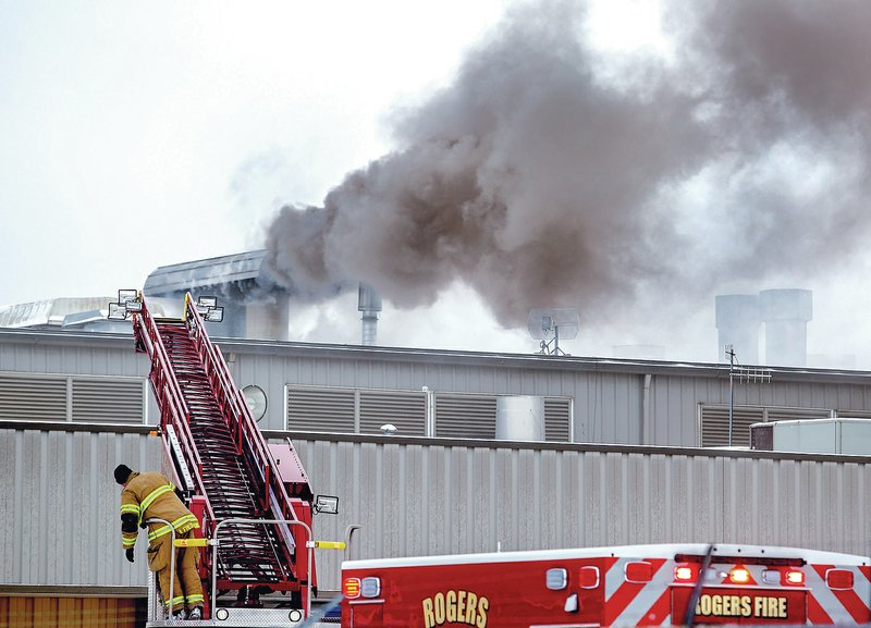 NWA Democrat-Gazette/JASON IVESTER Rogers firefighters work a fire Monday at Superior Industries on North Dixieland Road in Rogers. The fire broke out when sparks from a cutting torch got into the vent system and ignited metal dust, investigators said. A construction crew was in the process of removing line equipment.