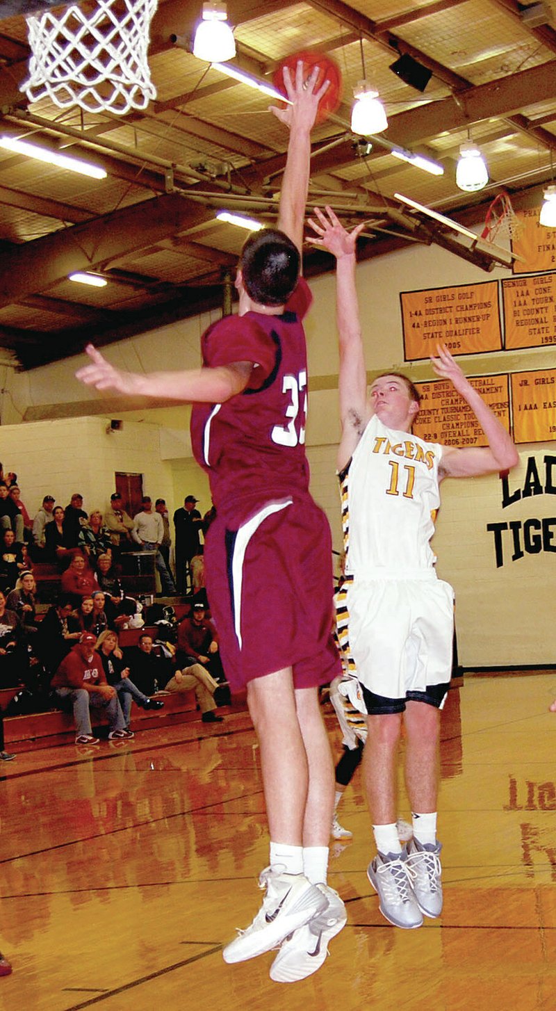 BEN MADRID ENTERPRISE-LEADER Prairie Grove forward Parker Galligan arcs a shot high towards the goal with Lincoln&#8217;s 6-foot-9 Shandon Goldman trying to block the attempt during the Tigers&#8217;, 50-44, victory on Jan. 20. In the rematch on Friday Goldman and the Wolves had their way winning 50-38.