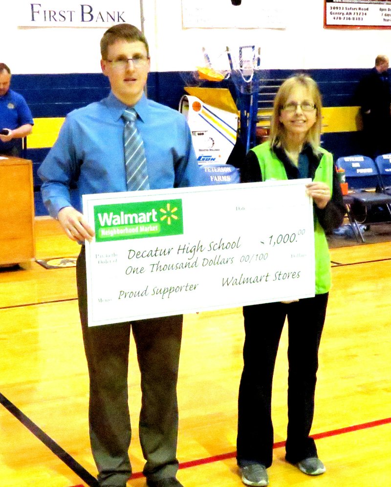 Walmart Supports Decatur Athletics John Unger (left), Decatur athletics director, receives a $1,000 check from Marie Miller, support manager for the Decatur Neighborhood Market, at halftime of the Mountainburg-Decatur basketball game at Peterson Gym in Decatur Jan. 6. Photo by Mike Eckels
