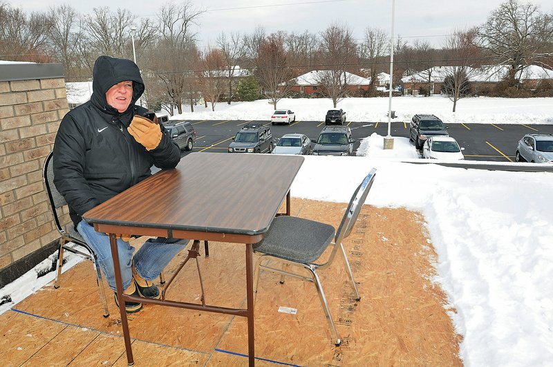NWA Democrat-Gazette/FLIP PUTTHOFF Michael Poore, superintendent of Bentonville public schools, works Tuesday from the roof of the Bentonville School Administration building to keep a pledge he made during a district food drive. Poore promised to work from the roof if enough food was donated to the Samaritan Community Center SnackPacks for Kids program to fill his office. The Bentonville Noon Rotary Club also donated $3,000 to the effort, Poore said.
