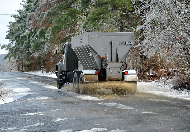 The Sentinel-Record/Mara Kuhn TREACHEROUS TRAVEL: A Garland County Road Department truck spreads sand Tuesday at the Amity-South Moore Road intersection after Monday’s ice storm. The 2 and a half ton truck can scatter sand 30 feet across a roadway.