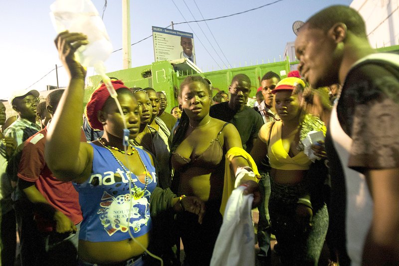 Injured revelers wait outside the General Hospital in Port-au-Prince, Haiti, early Tuesday, Feb. 17, 2015. At least 20 people on a music group's packed Carnival float in the Haitian capital were killed Tuesday when they were electrocuted by a power line, officials said. The accident occurred as thousands of people filled the streets of downtown Port-au-Prince for the raucous annual celebration. People at the scene said someone on the float used a pole or stick to move a power line so the float could pass under it.