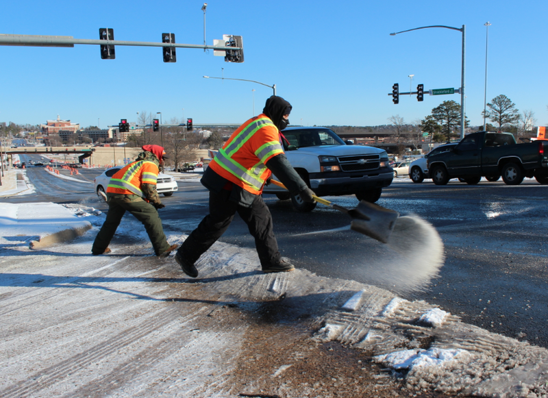 Victor Jordan, right, and Walter Diamond with the Arkansas Highway and Transportation Department spread ice melt on an icy Shackleford Road hill in west Little Rock Wednesday.