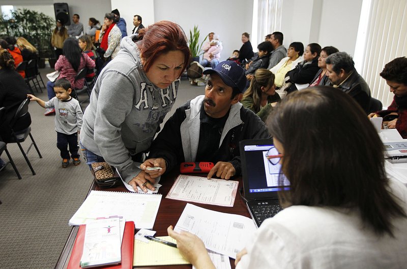 Jesus Rodriguez, center, and his wife Berta Salazar look over a problem with his documents while seeking help from Norma Canales Gomez, Tuesday, Feb. 17, 2015, at the Mexican Consulate office in McAllen, Texas. Mexican citizens living in the United States continued preparing their paperwork for deferment from deportation Tuesday despite a U.S. Federal Court decision to temporarily block President Obama's executive action on immigration.   MAGS OUT; TV OUT