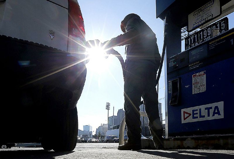 A man pumps gasoline for a motorist at a downtown Newark, N.J., gas station in January. 