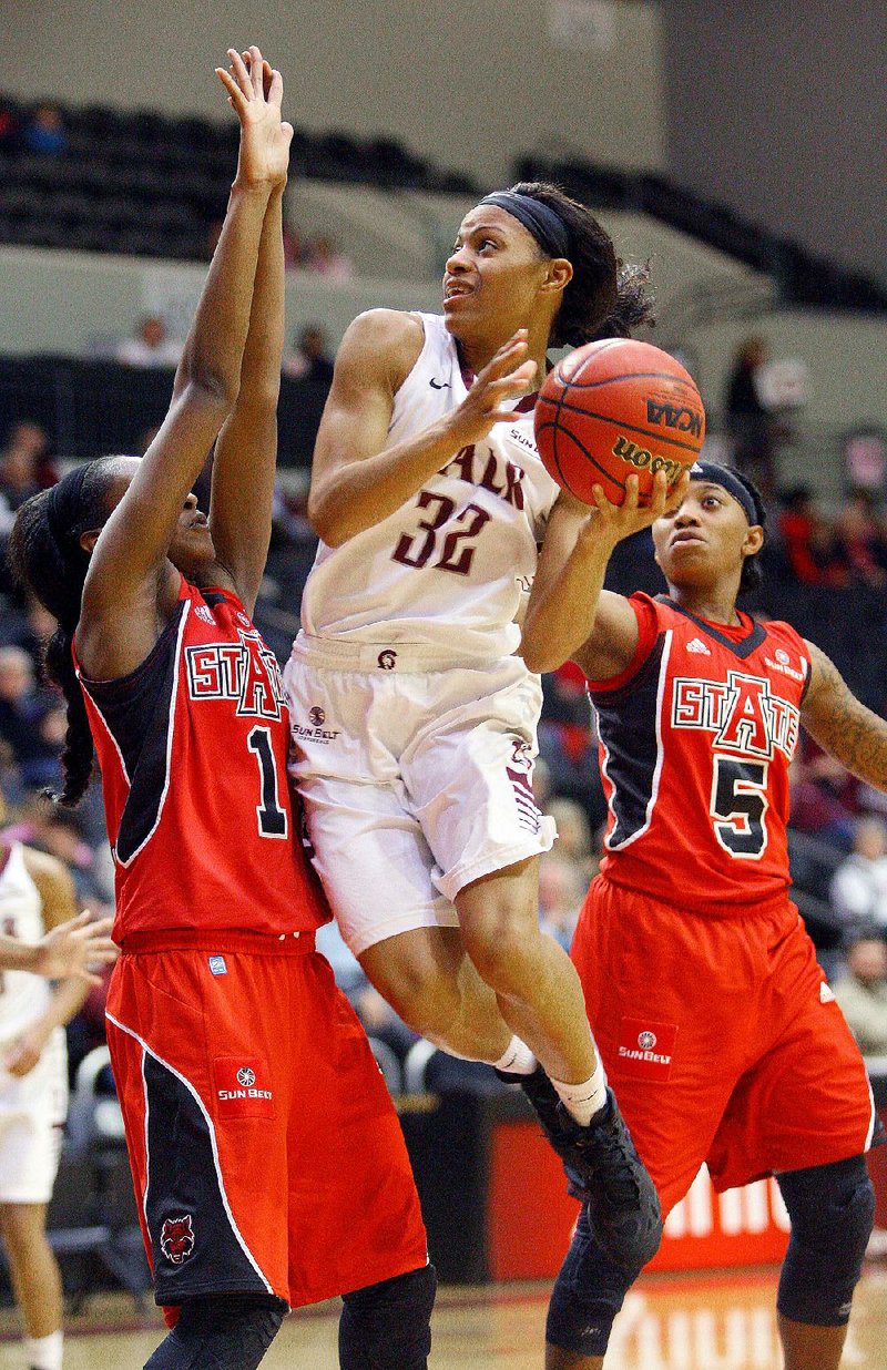 UALR guard Ka’Nesheia Cobbins (32) puts up a shot between Arkansas State defenders Lauren Bradshaw (1) and Brittney Gill (5) during Thursday night’s game at the Jack Stephens Center in Little Rock. Cobbins scored 11 points to help the Trojans hold on for a 63-61 victory. 