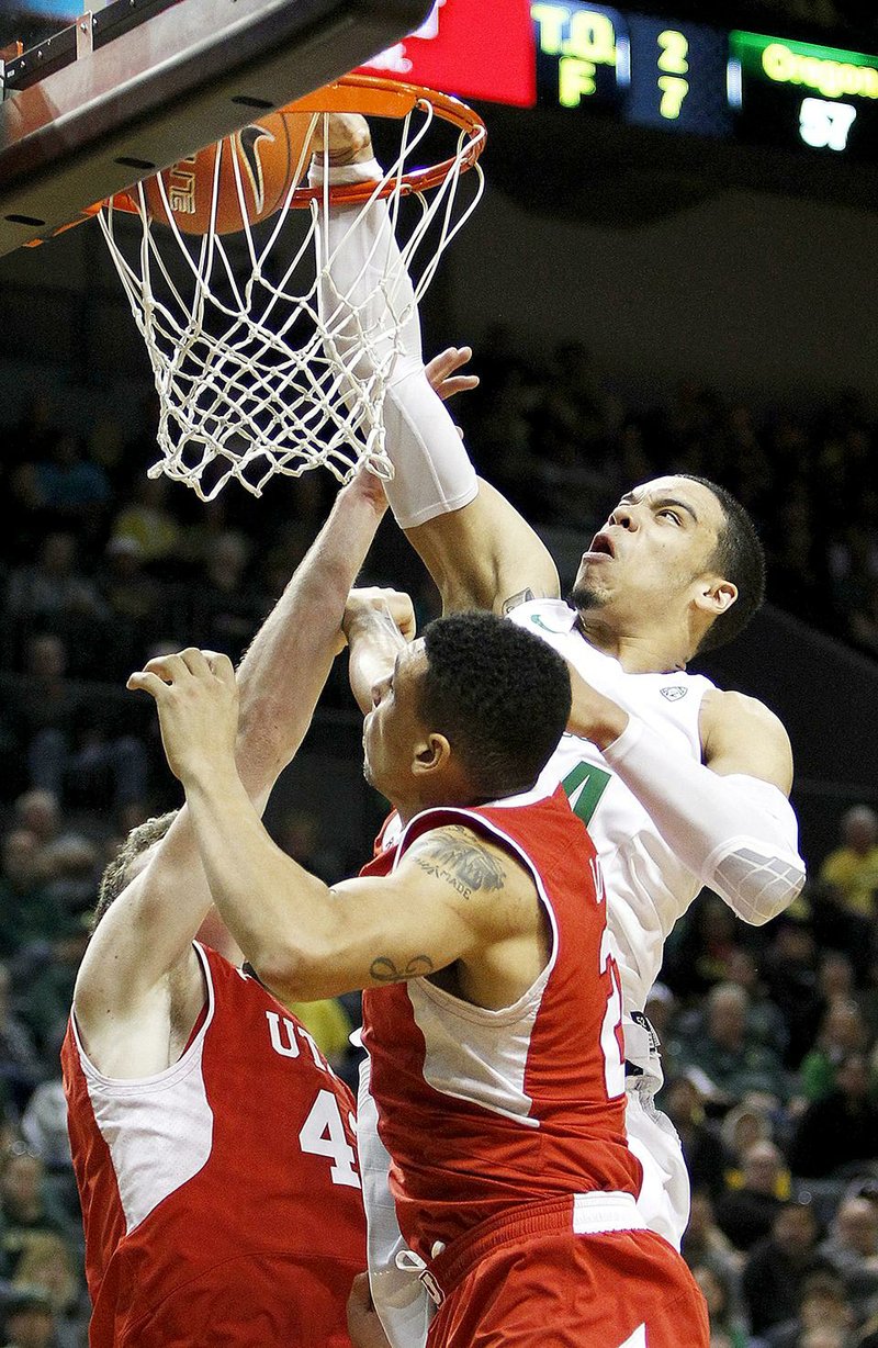 Oregon’s Dillon Brooks (right) dunks over Utah’s Jakob Poeltl (left) and Jordan Loveridge during the second half of Sunday’s game in Eugene, Ore. Brooks scored 11 consecutive points late in the second half and finished with 19 to lead the Ducks to a 69-58 victory over No. 9 Utah. 