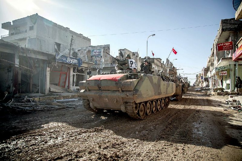Turkish army armored vehicles and tanks pass through the border town of Kobani, Syria, on Sunday as they return from evacuating troops who were guarding an Ottoman tomb. 