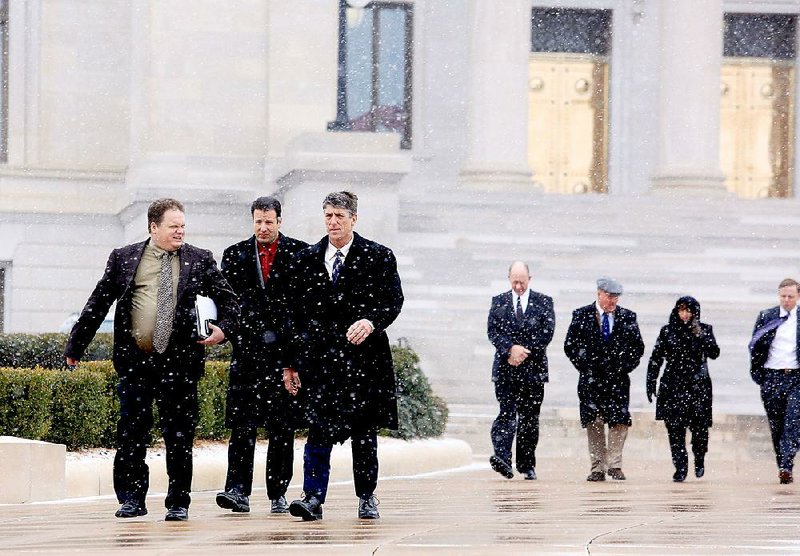 Legislators and others leave the state Capitol as snow falls in Little Rock on Monday. State offices closed at 12:45 p.m. because of the weather. Some of those shown are (from left) Rep. Nate Bell, R-Mena; Rep. David Meeks, R-Conway; and Rep. Kelly Linck, R-Flippin. 