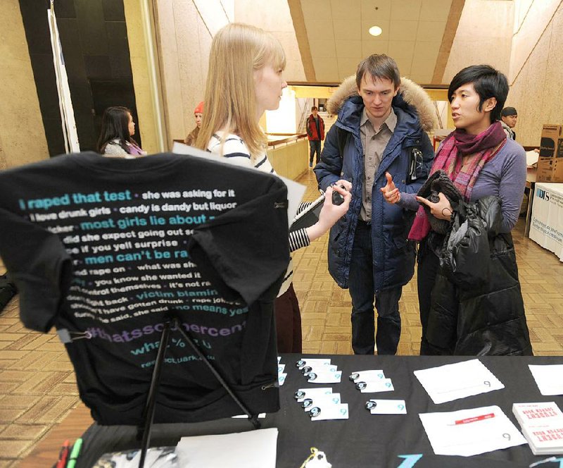 Olga Carson (left), a representative with Rape Education Services at the University of Arkansas at Fayetteville, speaks Tuesday with Mengjiao Liao (right) and Vitaly Romanov, both graduate students at the university. Carson was handing out T-shirts as a part of a rape awareness campaign.