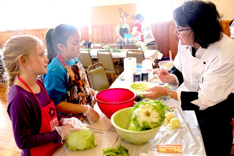 Photo by Brandy Cordeiro Kayla Philpott and Brynn Cordeiro receive instructions from Chef Janet Novotny at the Feb. 17 cooking class sponsored by the Gentry Senior Activity and Wellness Center. The fundraising event was held at the Gentry United Methodist Church.
