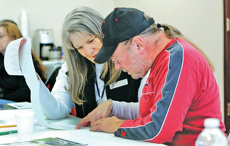 Art Hughes (right) and his wife, Cathy Hughes, review an election report Tuesday produced by Craig Seibert with Election Systems & Software while demonstrating the DS200 voting machine at the Washington County Courthouse in Fayetteville. The county Election Commission, county representatives and officials from other counties listened to the presentation to collect information on products available to replace voting machines, ballot counters and touch screens used now.