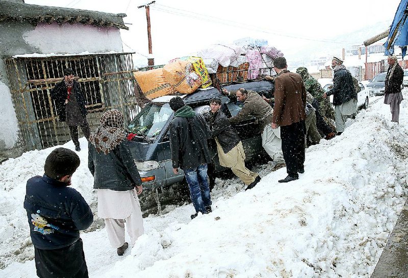 Afghans push a snow-stuck car Wednesday near the site of a deadly avalanche in Panjshir province north of Kabul.