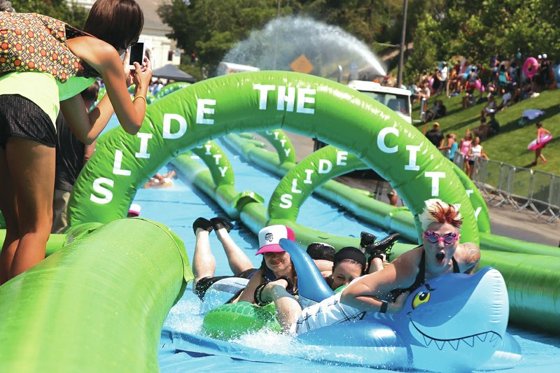 Event-goers slide down a 1,000-foot slip-and-slide event put on by Slide the City in Salt Lake City in July. The company is seeking permission to hold a similar event in Rogers. 