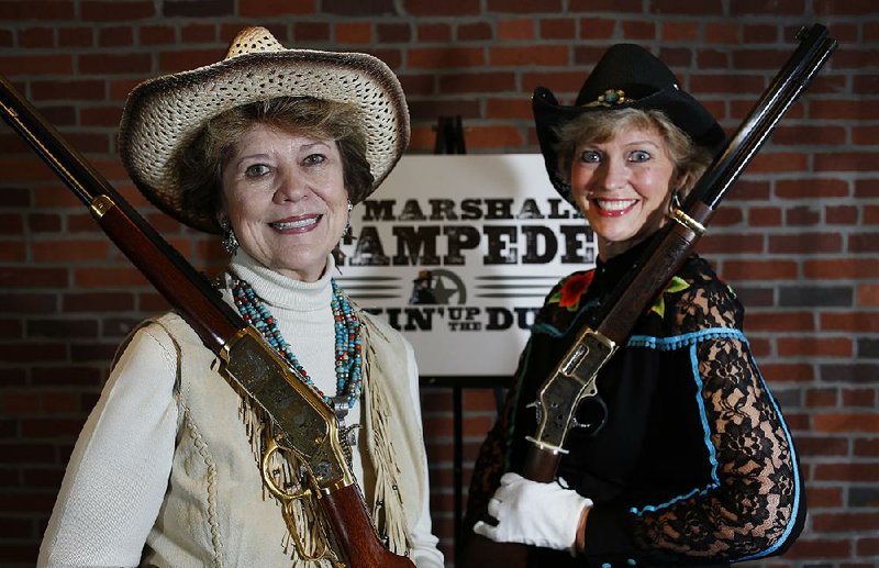 NWA Democrat-Gazette/DAVID GOTTSCHALK - 2/13/15 - Mary Young (left) and Kathy Babb display rifles Friday February 13, 2015 at the U.S. Marshals Office in Fort Smith that will be included in the activities of the U.S. Marshals Stampede Kickin' up the Dust fundraising gala on March 14, 2015.

