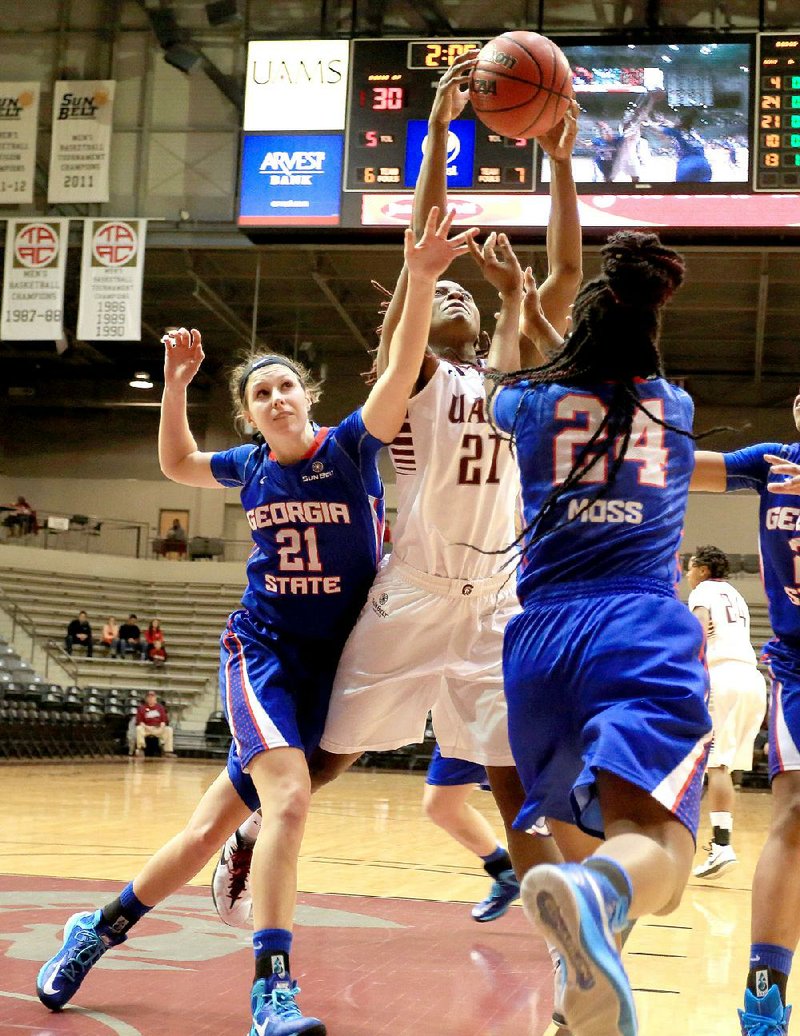 UALR’s Lexus Williams grabs a rebound away from Georgia State’s Morgan Jackson (21) and Gaby Moss (24) in the Trojans’ 56-39 victory Thursday at the Jack Stephens Center in Little Rock.