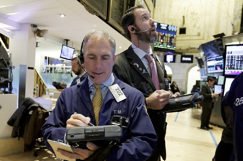 Timothy Nick (left), works with fellow traders Thursday on the floor of the New York Stock Exchange. Stock indexes remained near record highs Thursday amid mixed economic data. 