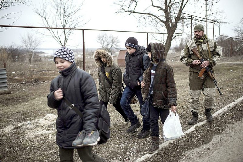 A Ukrainian soldier walks with schoolboys Thursday in the village of Chermalyk in Ukraine’s east, where a weapons pullback is expected to reduce violence. 