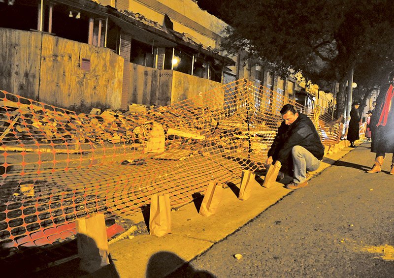 The Sentinel-Record/Mara Kuhn ANNIVERSARY CELEBRATION: Wally Mueller, of Hot Springs, lights luminaries in front of the Majestic Hotel during a commemoration event of the anniversary of the fire that destroyed the "yellow brick building" of the hotel complex on Feb. 27, 2014.