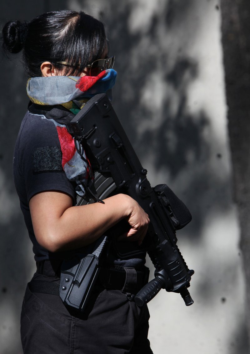 An armed and masked federal police officer stands guard as part of increased security outside the SEIDO, the organized-crime division of Mexico's Attorney General Office where high profile detainees are sometimes shown to the press in Mexico City, Friday, Feb. 27, 2015. The leader of the Knights Templar cartel, Servando "La Tuta" Gomez," one of Mexico's most-wanted drug lords, was captured early Friday by federal police in the capital city of Morelia, according to a Mexican official. It could not be confirmed if Gomez was inside the building.