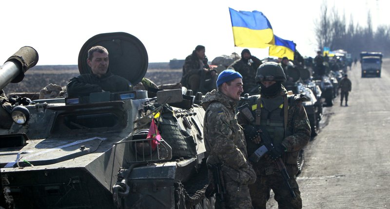 Ukrainian servicemen stand guard alongside armored vehicles with heavy weapons in tow and flying the Ukrainian on a road in the village of Fedorivka, eastern Ukraine, Friday, Feb. 27, 2015. Ukrainian and Russian-backed separatist forces drew back some heavy weapons from the front line in the east Friday in compliance with a cease-fire deal, although officials in Kiev accused rebels of falling short of requirements. 