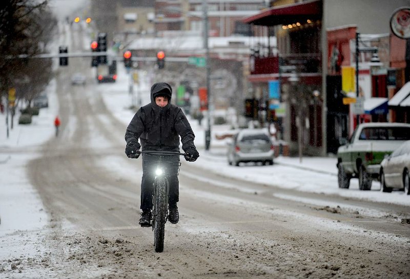 NWA Democrat-Gazette/ANDY SHUPE - A cyclist makes his way up West Dickson Street as snow falls Saturday, Feb. 28, 2015, in Fayetteville.