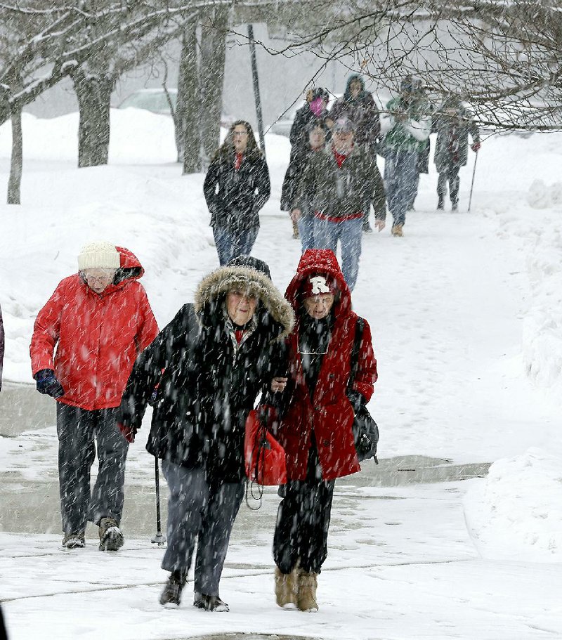 People walk in falling snow Sunday, March 1, 2015, in Piscataway, N.J. The National Weather Service has issued a winter storm warning for most of central and southern New Jersey, while the rest of the state is under winter weather advisory. Forecasters say a wintry mix of snow, sleet, freezing rain and rain started falling across the state late Sunday morning and should continue through early Monday. (AP Photo/Mel Evans)