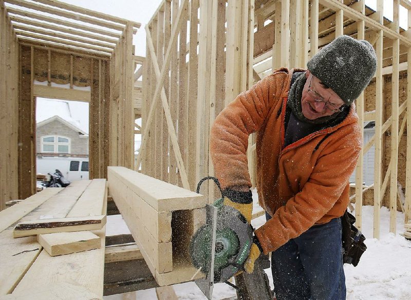 In this Wednesday, Feb. 18, 2015 photo, carpenter Joe Tominc cuts wood for a post on a home under construction in Pepper Pike, Ohio. The Commerce Department reports on U.S. construction spending in January on Monday, March 2, 2015. (AP Photo/Tony Dejak)