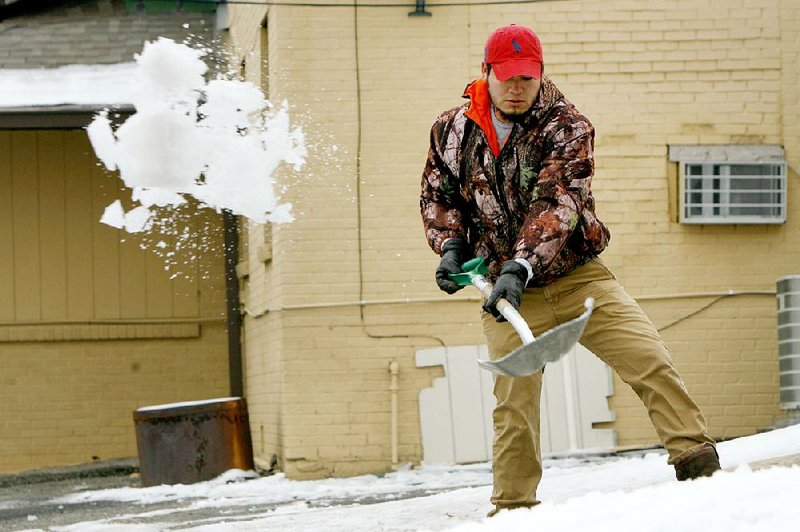 NWA Democrat-Gazette/DAVID GOTTSCHALK - 3/2/15 - Ice flies off of the shovel of Eduardo Nunez as he clears the driveway of Lizzie B's Vintage Shoppe on College Avenue in Fayetteville Monday March 2, 2015. The elimination of ice and snow from the weekend winter weather was aided the the afternoon above freezing temperatures.

