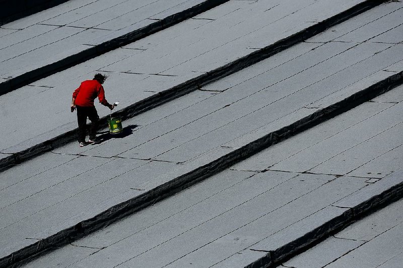 A worker installs insulation on the roof of a school building Tuesday in the Athens suburb of Tavros. The Greek economy appears to be heading for another recession, analysts say. 