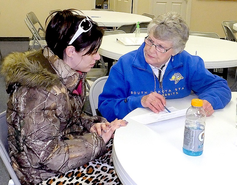 Lynn Atkins/The Weekly Vista Volunteer Mary Eitreim, right, talks to a woman who was picking up groceries for a family that includes young children at the Oasis Food Bank inside Village Bible Evangelical Free Church last week